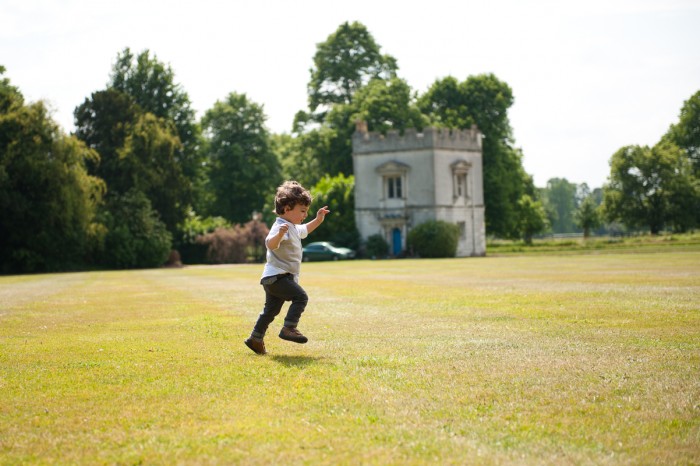 Small boy running through grass during wedding at Syon House