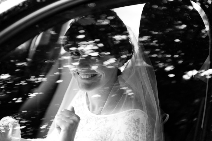 Dappled black and white portrait of bride arriving at country church