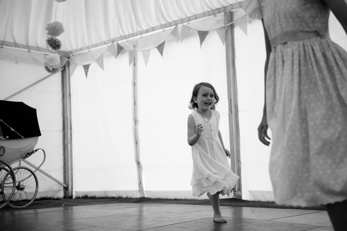 Little girl running around he dance floor during a marquee wedding