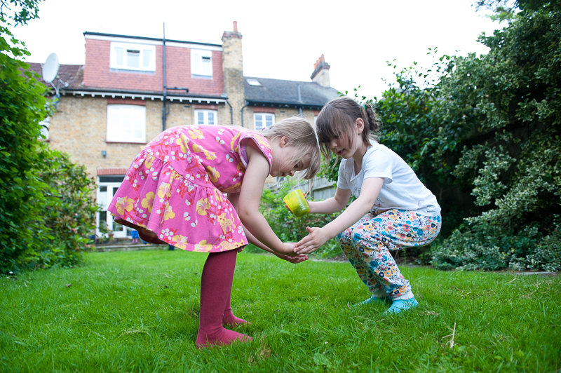 Cousins looking at ladybird during family photo shoot in Palmers Green