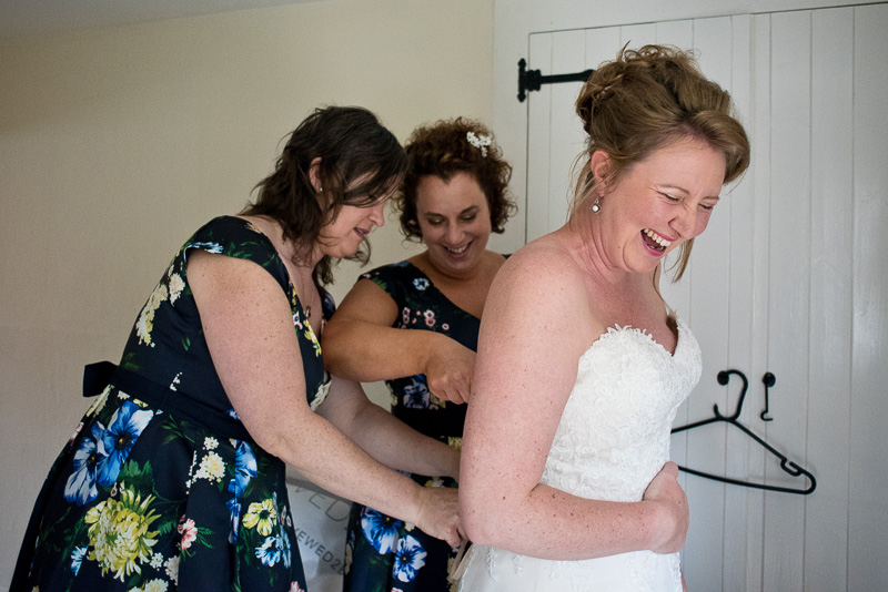 Bridesmaids helping bride into dress for a yurt wedding