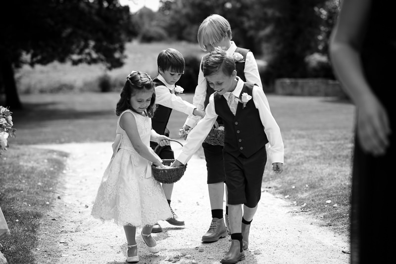 Flower girls and ringbearers throwing flower petals on aisle