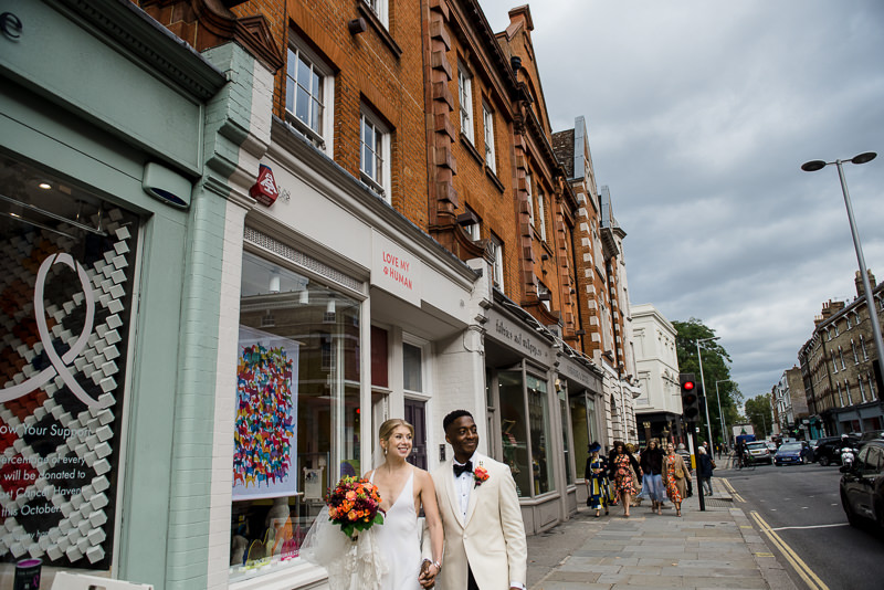 Bride and groom walk the streets of Chelsea with their guests
