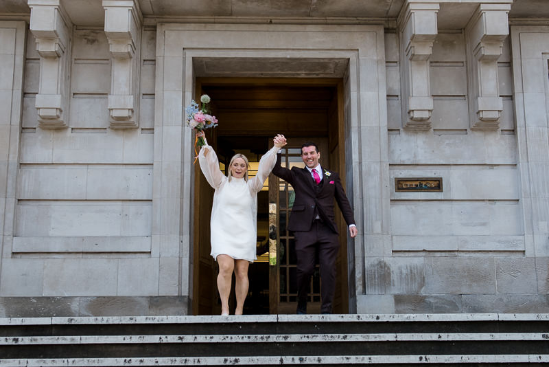 Bride and groom walk down the steps at Hackney Town Hall