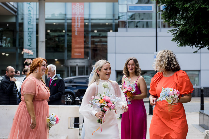 Bride arrives at Hackney Town Hall surrounded by bridesmaids in colourful dresses